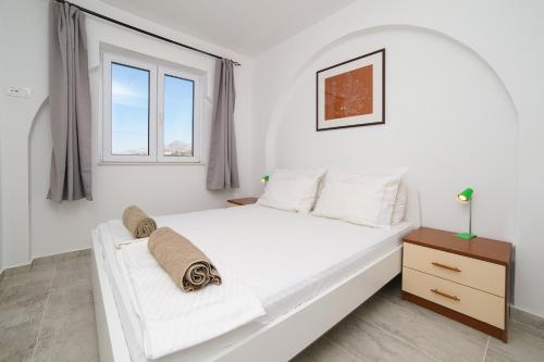 a white bedroom with a bed and a window at Gustav - Sea view apartment with balcony in Cavtat