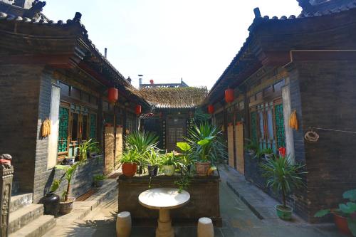 a courtyard of a building with potted plants at Pingyao Laochenggen Inn in Pingyao