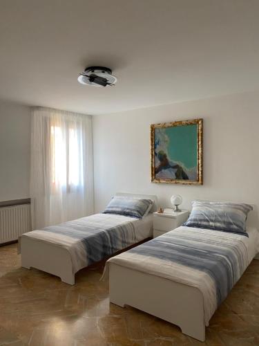 - 2 lits dans une chambre blanche avec une photo sur le mur dans l'établissement Casa di Angela, à Chioggia