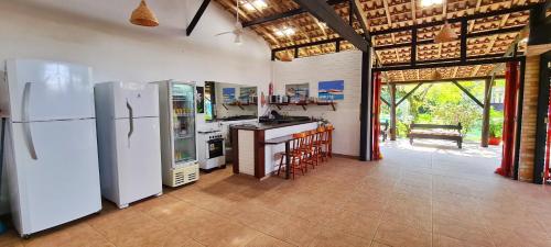 een keuken met 2 koelkasten en een aanrecht met stoelen bij Pousada Areias do Embaú in Guarda do Embaú