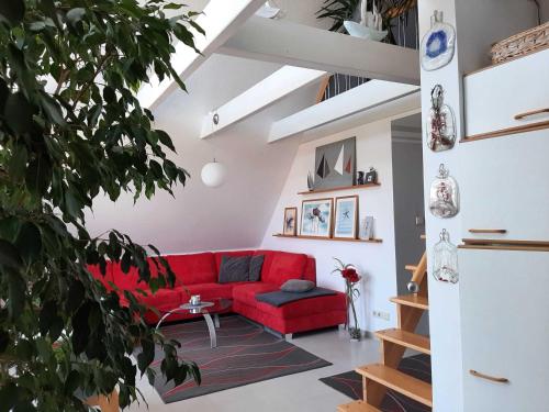 a red couch in a living room with a plant at Ferienwohung Galerie in Elmenhorst