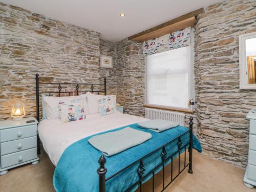 a bedroom with a bed and a stone wall at Curlews Cottage in Looe