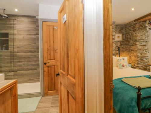 Un baño con cama y ducha de cristal. en Curlews Cottage, en Looe