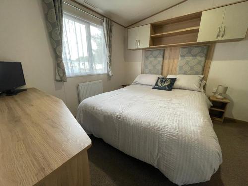 Un dormitorio con una gran cama blanca y una ventana en 'Oakley' Boat of Garten Holiday Park en Boat of Garten