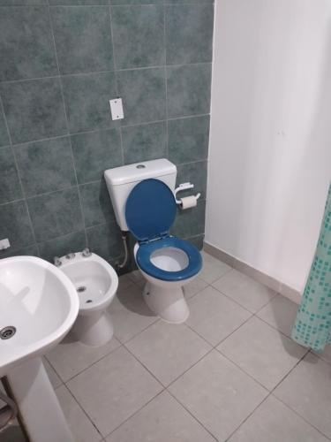 La salle de bains est pourvue de toilettes bleues et d'un lavabo. dans l'établissement CASABLANCA, à El Ceibal