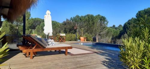 a patio with a bench and an umbrella and a pool at Ying Yang Monte da Lua in Comporta