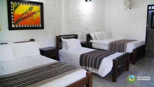 a hotel room with two beds and a painting on the wall at Finca Hotel los Nogales in Quimbaya