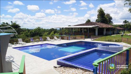 a swimming pool with chairs and a house at Finca Hotel los Nogales in Quimbaya