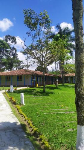 a building with a green yard with trees in front of it at Finca Hotel los Nogales in Quimbaya