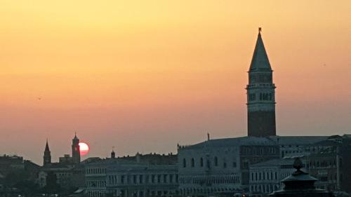 a sunset over a city with a clock tower at Beatiful modern flat Venice centre with private lounge green area relax in Venice