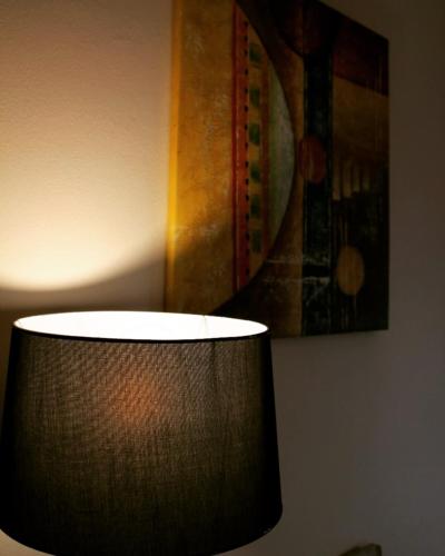 a lamp in a room with a painting on the wall at Hotel Ambasador Garden in Lezhë