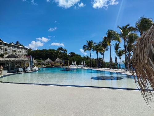 uma grande piscina com palmeiras num resort em Perle marine Diamant em Le Diamant