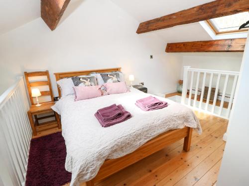 a bedroom with a bed with pink pillows on it at The Mistle Carr Farm in Ripponden