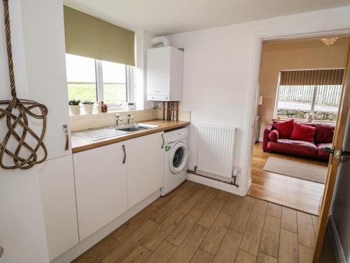 a kitchen with a sink and a washing machine at Bodfan Peniel in Llanerchymedd