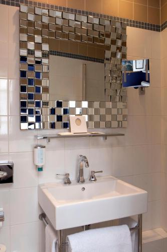 une salle de bain avec un lavabo et un miroir dans l'établissement Petit Madeleine Hôtel, à Paris