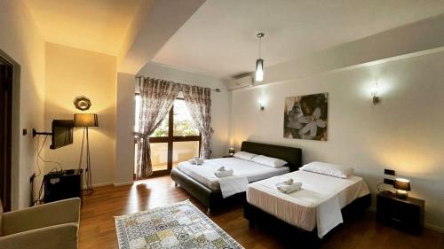 1 dormitorio con 2 camas, sofá y ventana en Hotel Ambasador, en Lezhë