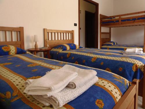 1 dormitorio con 3 camas y toallas. en AGRITURISMO Cré Seren en Susa