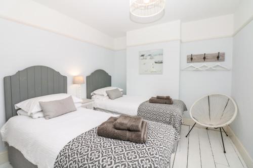 a bedroom with two beds and a chair at Cool Stone Cottage in Instow