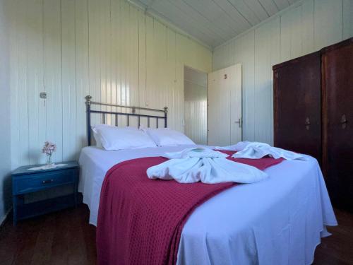 a bedroom with two beds with white sheets and a red blanket at Casa Foresti in Bento Gonçalves