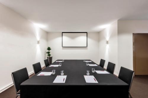 a conference room with a black table and chairs at Fable Christchurch in Christchurch
