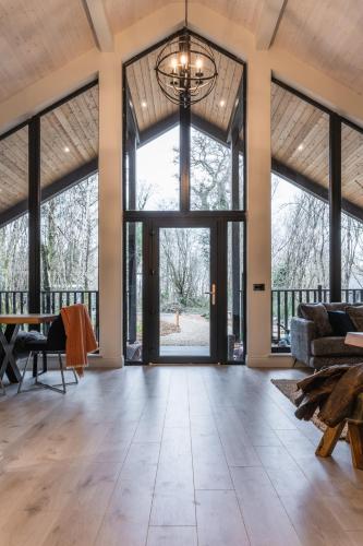 an open living room with large windows and a chandelier at Drumhierny Woodland Hideaway in Leitrim