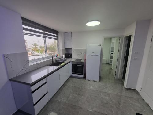 a kitchen with white cabinets and a white refrigerator at Diamond Suites Eilat in Eilat