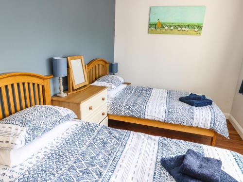 a bedroom with two beds and a picture on the wall at Crud Yr Awel in Amlwch