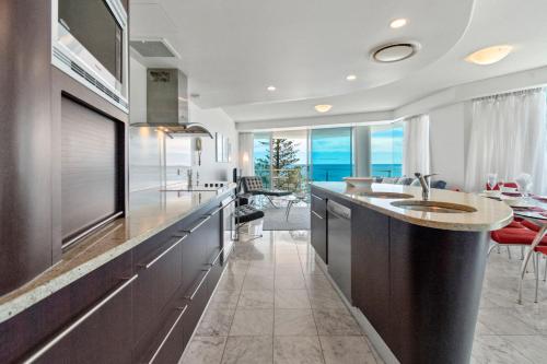 a kitchen with a sink and a counter with a table at Sirocco 608 by G1 Holidays in Mooloolaba