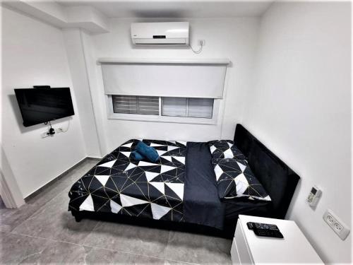 a bedroom with a black and white bed and a tv at Diamond Suites Eilat in Eilat