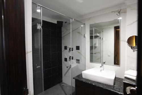 a bathroom with a sink and a glass shower at Hotel Saffron Leaf in Dehradun