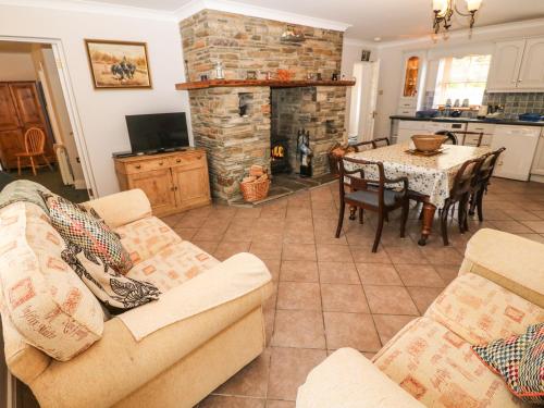 a living room with a couch and a table with a fireplace at Lis-Ardagh Cottage 1 in Skahanagh