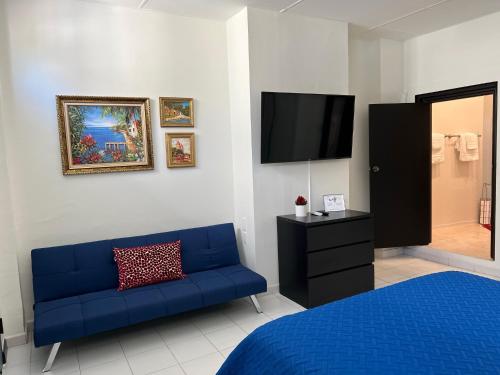 a bedroom with a blue couch and a flat screen tv at 310Guest-House La Vida in San Juan