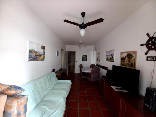 uma sala de estar com um sofá e uma ventoinha de tecto em Apartamento 500M da Praia Enseada, Guarujá no Guarujá