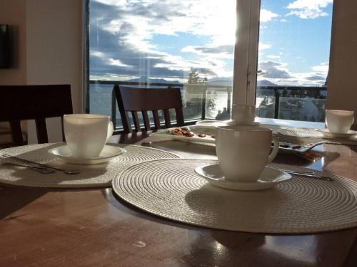 a table with two cups on a table with a view at Civico Apartment in San Carlos de Bariloche
