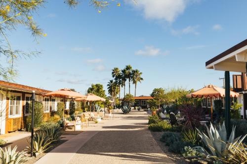 a walkway with umbrellas and tables and palm trees at Skyview Los Alamos - 21 & Over Pool in Los Alamos