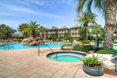 a swimming pool in a resort with palm trees at Village Retreat in Destin