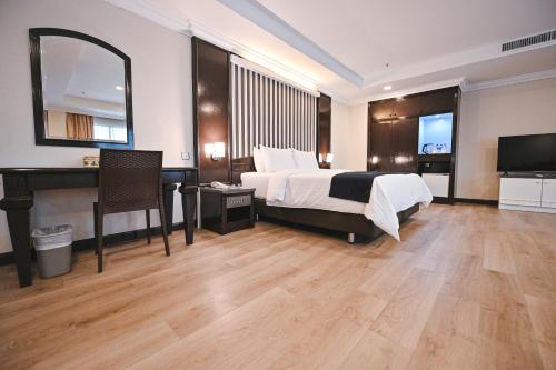 a bedroom with a bed and a desk and a television at PRIME CITY HOTEL KLUANG in Kluang
