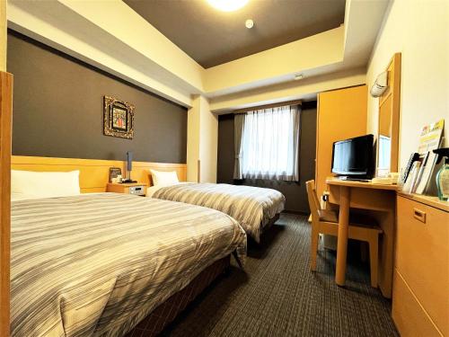 Habitación de hotel con 2 camas y escritorio con TV. en Hotel Route-Inn Hakata Ekimae -Hakataguchi- en Fukuoka
