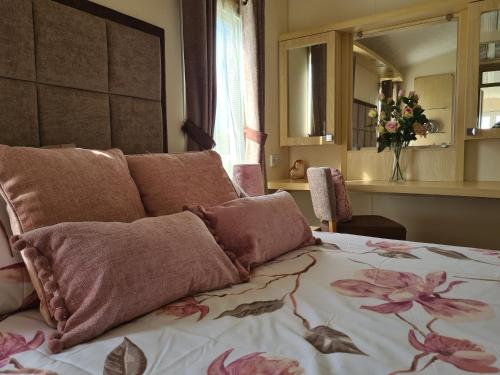 a bedroom with a bed with pink flowers on it at Beautiful 2 bedroom caravan, holiday park Tenby in Pembrokeshire