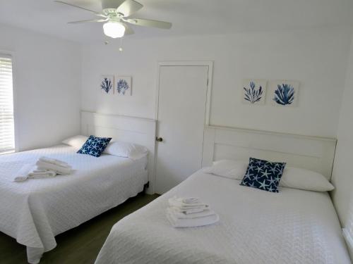 two twin beds in a room with a ceiling fan at Saltaire Cottages in Kitty Hawk Beach