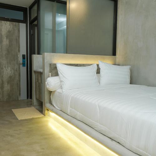 - une chambre avec un grand lit blanc et un miroir dans l'établissement Dparagon Menteng Jakarta, à Jakarta