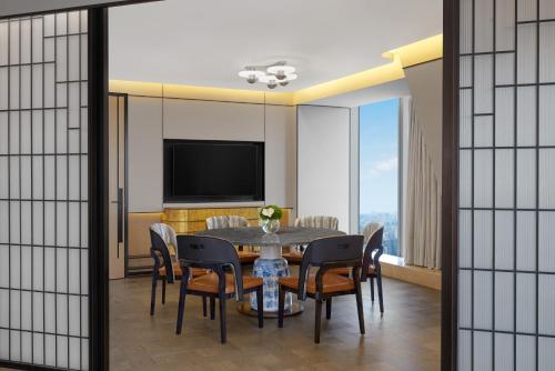 a dining room with a table and chairs and a television at Conrad Shanghai in Shanghai