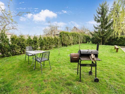a grill and a table and chairs in a yard at Cozy Chalet with Garden in Beauraing