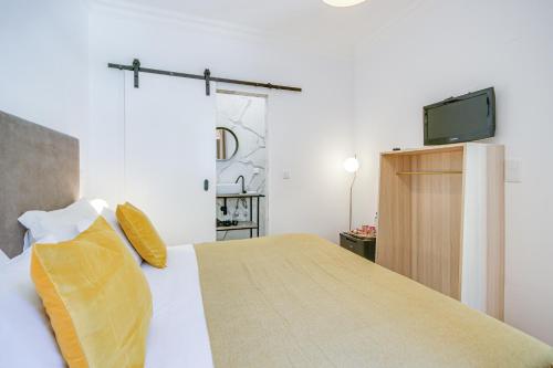 a bedroom with a bed with a tv on the wall at Alvalade Palace in Lisbon