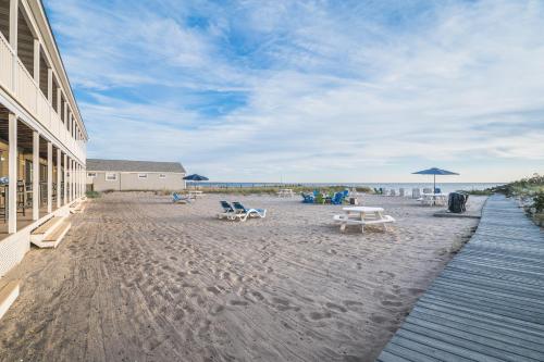 a beach with chairs and tables and an umbrella at Sandbars Inn in North Truro