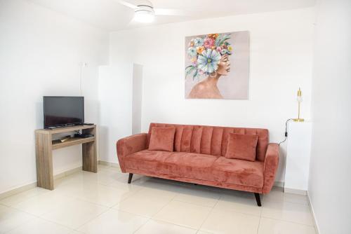 a living room with a orange couch and a tv at Suite jacuzzi et vue panoramique - BED AND COFFEE AIRPORT in Ducos