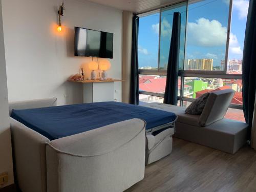 Cette chambre comprend un lit, une chaise et une télévision. dans l'établissement PENTHOUSE 10 MIN port croisière et aéroport, à Pointe-à-Pitre