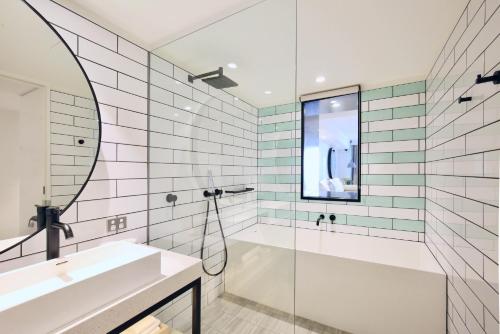 a bathroom with a tub and a sink and a mirror at Miss Baker's Boutique Accommodation Bondi in Sydney