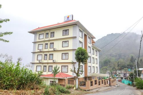 a tall building with a tree in front of it at MySpace Banari Residency in Namchi