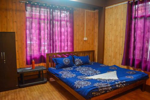 una camera con letto blu e tende viola di The Sangam Homestay a Kalimpong